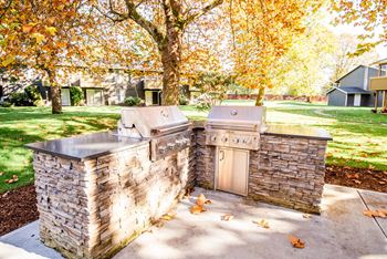 A stone outdoor kitchen with a grill and sink 